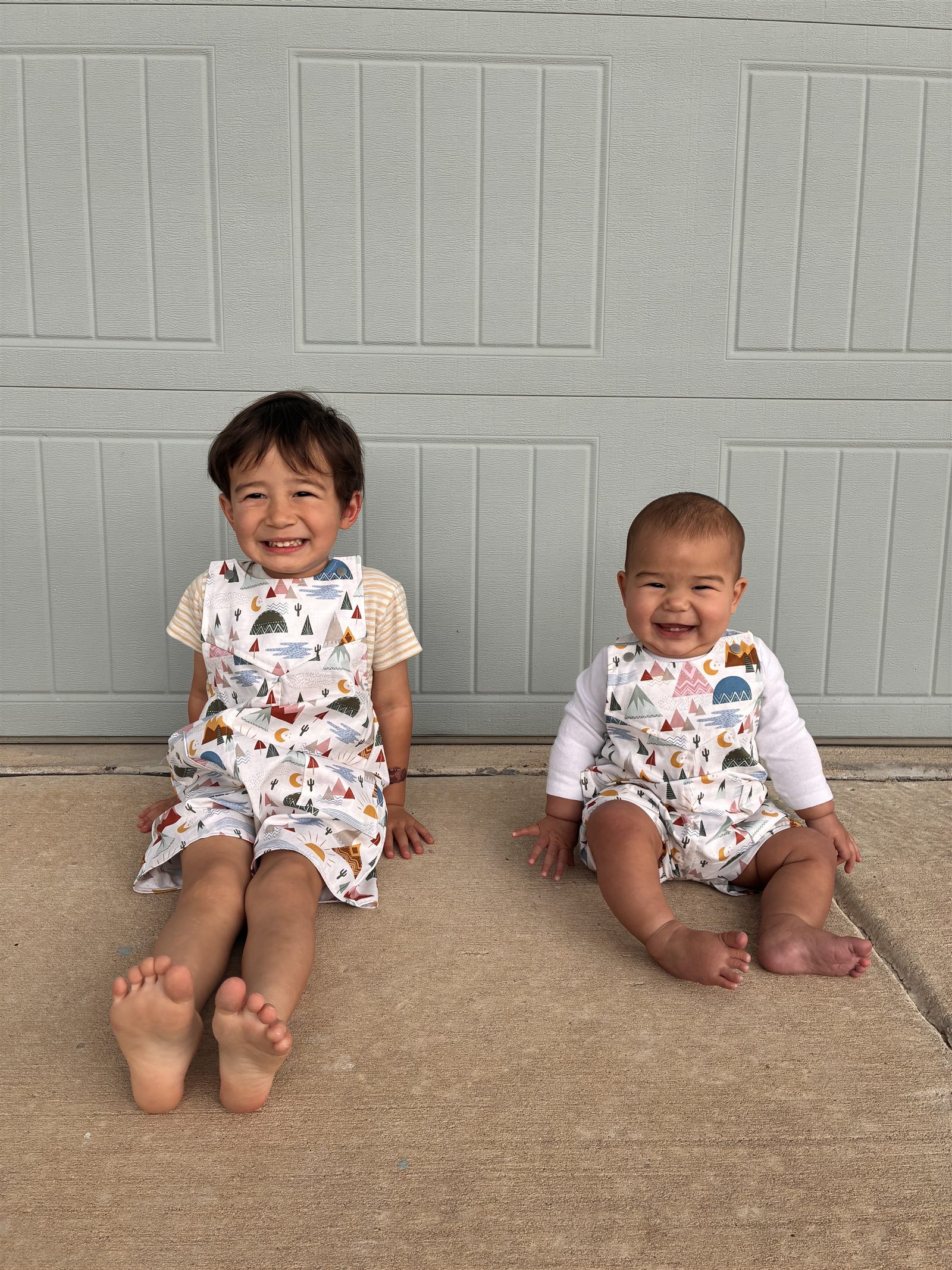 Two children in matching handmade mountain-print rompers sitting together