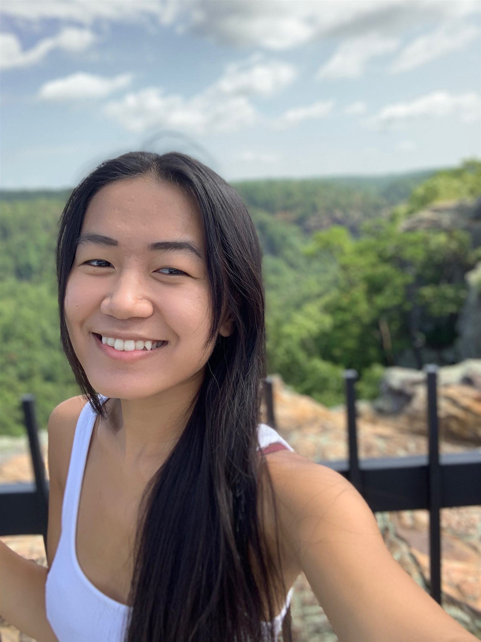 Hannah smiling outdoors by a green overlook